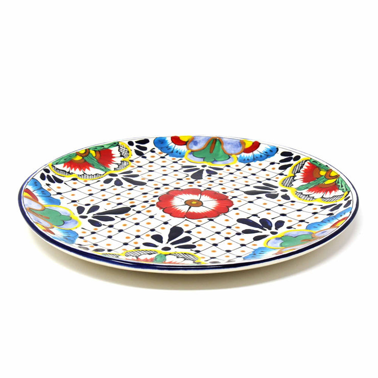 Close-up of artisan hand-painted dinner plate with dots and floral motif