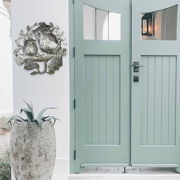“close-up view of owl faces in Haitian upcycled metal wall sculpture”